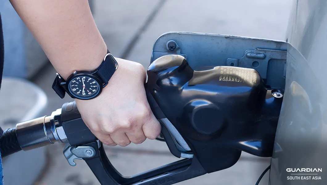 reducing fuel consumption man with watch reflling car with gasoline