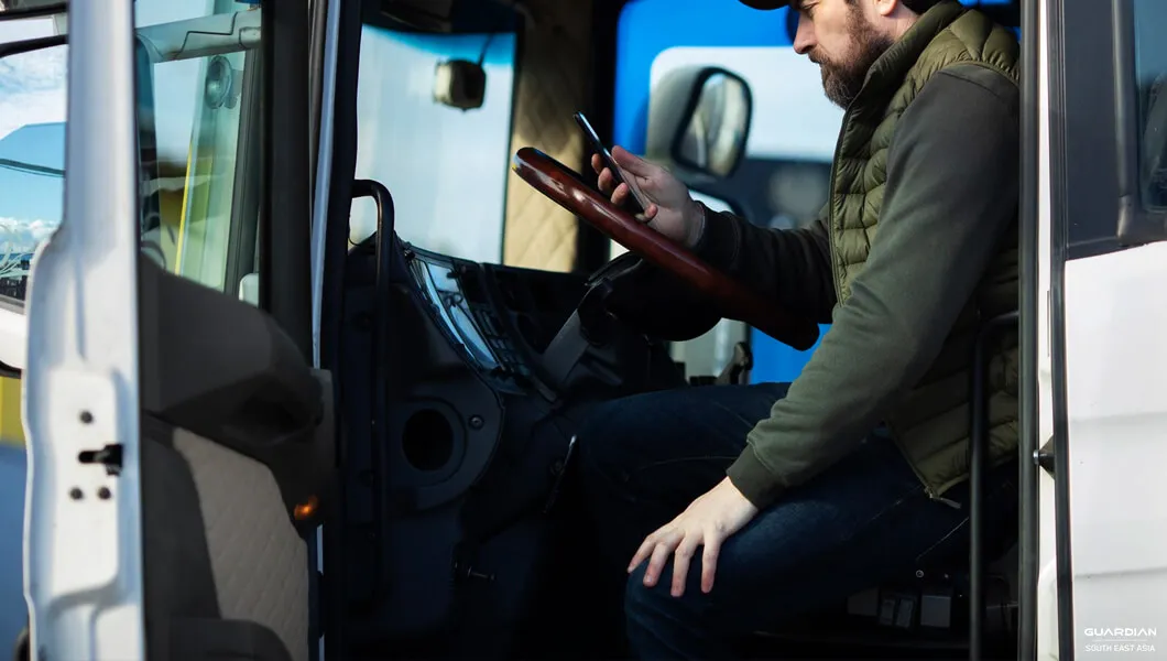 Optimising Your Fleet And Cutting Maintenance Costs man in truck using mobile phone